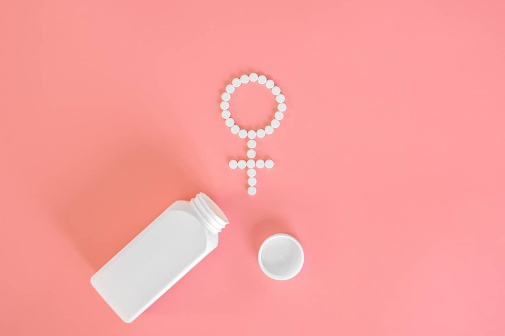 a white bottle next to a symbol of a woman sign of menstruation bleeding